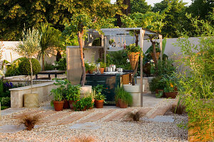 Kiesgarten mit Außenküche - Holzschwellenweg mit Kräutern in Behältern, Pergola