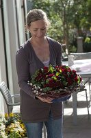 Woman with Primula Belarina 'Valentine' (Stuffed Primroses) with wreath of Salix