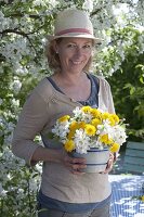 Frau hält Strauß aus Malus (Zierapfel) und Taraxacum (Löwenzahn)