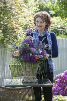 Frau steckt Strauß aus Allium 'Globemaster' (Zierlauch), Rosa (Rosen)