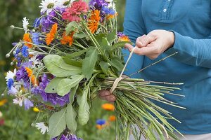 Woman tying a colourful bouquet of summer flowers