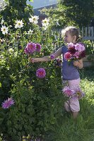 Mädchen pflückt Blumen für Spaetsommerstrauss