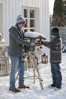 Mother and son filling bird food into the bird feeder