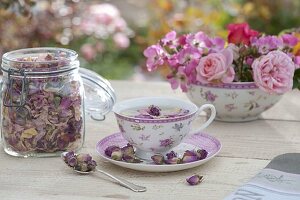 Rosentee in Tasse mit Rosendekor, Schale mit Blüten von Rosa