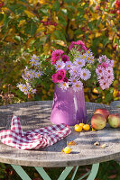 Small seating area with bouquet of asters in front of ironwood tree and ornamental apples