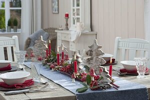 Gedeckter Tisch mit kleinen Weihnachtsbaeumen aus Birkenrinde, roten Beeren