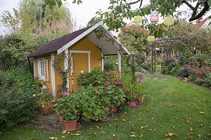 Garden house with geraniums in pots