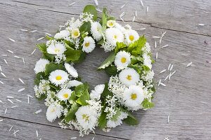 Tying a wreath of daisies and herbs