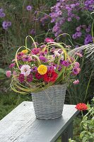 Laendlicher Strauss aus Zinnia (Zinnien) und Gräsern in Korb-Vase