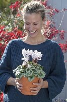 Frau mit Cyclamen (Alpenveilchen) im Terracotta - Topf