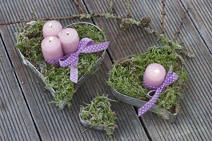 Candles in moss-filled heart shapes and purple ribbon