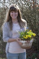 Woman bringing clay pot with Scilla, Eranthis