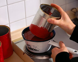 Tin dipped in red wax (1/2). Dip a clean tin can in liquid wax.