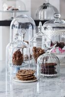 Vegan cookies and cupcakes under glass domes in a café
