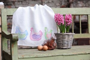 Hand-made table runner with pattern of hens, potted hyacinths, cake and eggs on wooden bench
