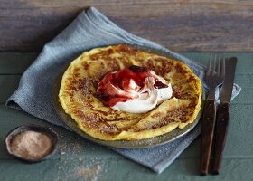 A pancake with cream and plum jam