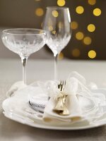 A Christmas table setting with a white bow and crystal glasses