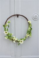 Rustic wreath made from rusty wire and tulips on cupboard door