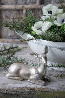 Silver doe ornament in front of arrangement of larch twigs and anemones in soup tureen