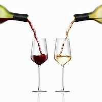 Red and white wine being poured into wine glasses side by side