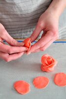 A woman's hands forming red marzipan roses