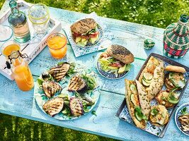 Gedeckter Tisch im Garten mit Sandwiches und Getränken