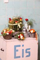 Blumengestecke in Küchenutensilien auf einem alten Eiswagen