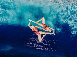 Two synchronised swimmers forming a shape in the water (seen from above)