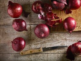 Red onions on chopping board and wooden table with knife