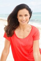 A brunette woman wearing a red T-shirt on the beach