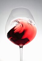 Red wine creating a wave in a glass