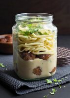Meatballs and tagliatelle in a glass jar with soy cream and fresh parsley
