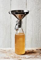 Selbstgemachter Kombucha-Tee in Flasche mit Trichter