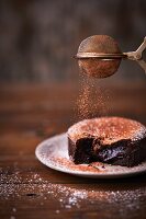 Chocolate Fondant Cake wird mit Kakaopulver bestreut
