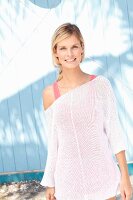 Blonde Frau in pinkfarbenem Top und weißem Strickpullover