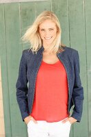 A blonde woman wearing a red top, a denim jacket and white trousers