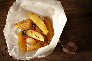 Homemade potato wedges in paper with garlic