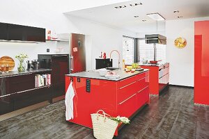 Grosszügige Küche mit zwei roten Kücheninseln und schwarzer Küchenzeile