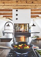 A kitchen island with a gas oven and granite worktop with a gas fire in the background