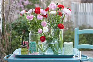 Ranunculus bouquets in preserving jars on tray
