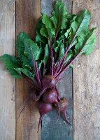 Several fresh beetroots with leaves on a wooden background
