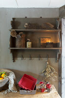 Red and grey baking trays and cups on worksurface below wall-mounted wooden shelves