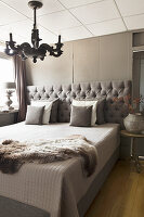 Bed with button-tufted headboard in small bedroom in shades of grey