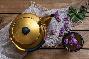 A teapot and cup of green tea with mint and edible flowers