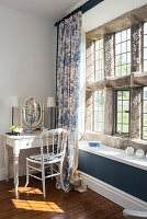 Antiker Schminktisch und Stuhl vor rustikalem Fenster mit moderner Ablage und Toile De Jouy Vorhang