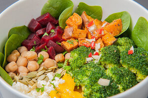 Buddha bowl with baby spinach, sweet potatoes, broccoli, mango, feta cheese, chickpeas and beetroot