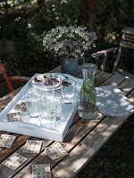 A homemade scrabble coaster and a wooden tray with glasses on a garden table