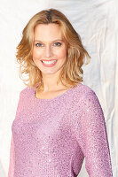 Blonde Frau in fliederfarbenem Pulli mit Lurex und Pailletten