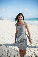 Junge Frau in grauem Wickelkleid am Strand