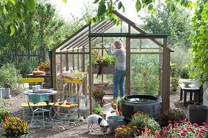 Glass house with seating place and water barrel in the garden